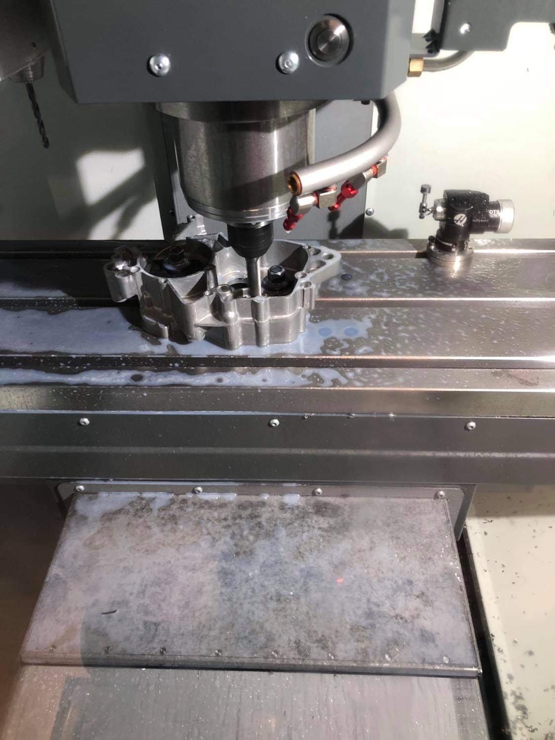 Aluminium housing being milled under coolant on the CNC machine